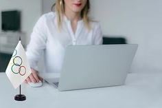 a woman sitting in front of a laptop computer with a flag on the table next to her