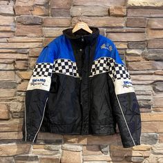 Vintage Sno Pro Racing Jacket | Vintage Jacket | Vintage Racing Jacket | Royal Sportswear | Blue and Black Jacket with Checkers | NPQ-2037 Used - stains throughout light coloured sections (blue and white areas), Loose threads on embroidered writing, general wear and tear L Size for Men, Please refer to photos for measurements Chest 27" Length 28 1/2" Outer Shell: 100% Nylon Lining: 100% Polyester We only ship to the US and Canada. All our items of vintage condition. Most of the items have minor Casual Black Skiing Outerwear, Sporty Winter Motorcycle Outerwear, Sporty Winter Motorcycling Outerwear, Black Long Sleeve Outerwear For Skiing, Black Racing Outerwear For Sports, Blue Winter Motorcycle Outerwear, Blue Winter Motorcycling Outerwear, Winter Biker Outerwear For Sports, Black Racing Outerwear For Streetwear