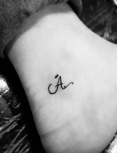 a small tattoo on the foot of a woman's foot, with an initial