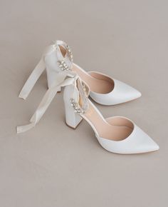 two pairs of white shoes with bows on them