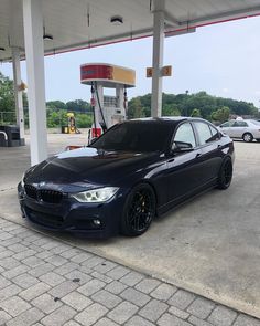 a black bmw is parked at a gas station