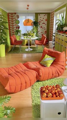 a living room filled with orange furniture and lots of greenery on the walls,