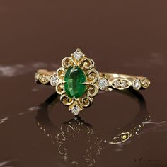 an emerald and diamond ring sitting on top of a table