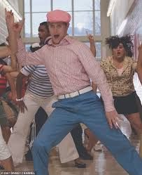 a group of people dancing in a dance studio with one man wearing a pink hat