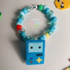 a bracelet made out of beads with a pacman charm attached to it, sitting on top of a table