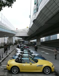 a yellow sports car parked on the side of a road in front of an overpass