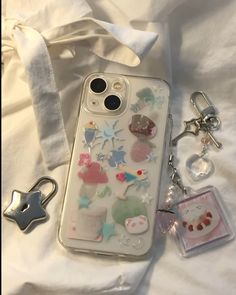 an iphone case with many different things attached to it, sitting on top of a bed