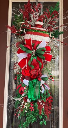 a christmas wreath is hanging on the front door with red and green decorations around it