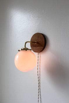 a wall mounted light on the side of a white wall next to a wooden clock