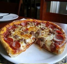 a pepperoni pizza on a plate with one slice missing from the rest of it