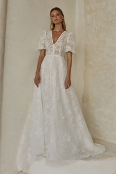 a woman in a white wedding dress standing against a wall