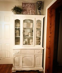 a white china cabinet with glass doors and drawers