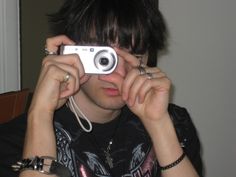 a young man holding up a camera to take a photo with his headphones on