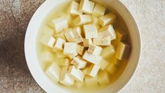 a bowl filled with cubes of tofu sitting on top of a countertop