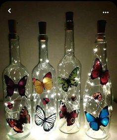 three empty bottles with butterflies on them and some lights in the bottom one is lit up