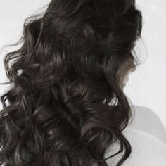 the back of a woman's head with long, curly hair and no makeup