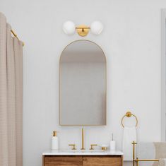 a bathroom with a sink, mirror and gold faucet