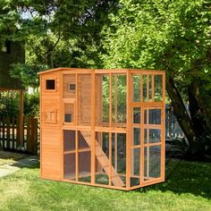 a chicken coop in the grass next to a tree