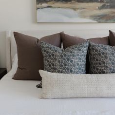 a bed with two pillows on it and a painting above the headboard in the background