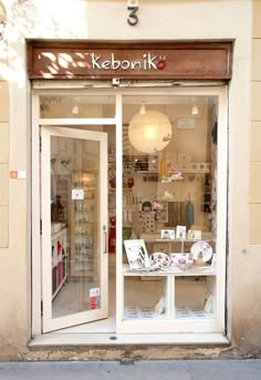 a store front with an open window on the side of the street in front of it