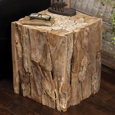 a table made out of tree trunks with a lamp on top and eyeglasses resting on it