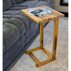 a wooden table sitting on top of a carpeted floor next to a gray couch