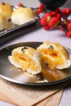 two pastries sitting on top of a metal plate next to red berries and paper