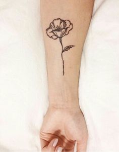 a woman's arm with a small flower tattoo on the left side of her wrist