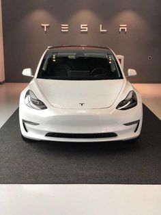 a white tesla car is on display in a showroom