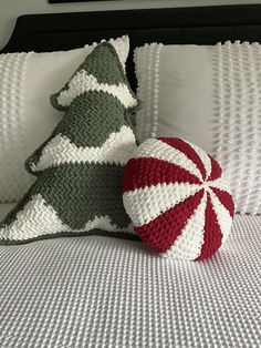 a crocheted christmas tree pillow sitting on top of a bed next to pillows