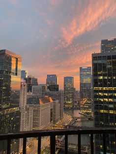 the city skyline is lit up at night with pink clouds in the sky and skyscrapers on either side