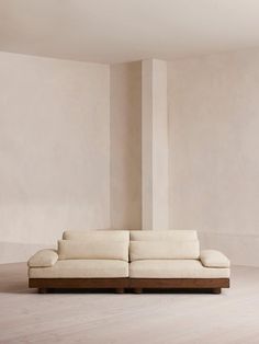 a white couch sitting on top of a hard wood floor next to a tall wall