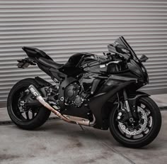 a black motorcycle parked in front of a garage door