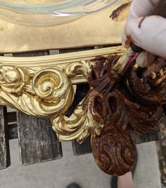 a person is painting a gold frame on a wooden bench with brown and white paint