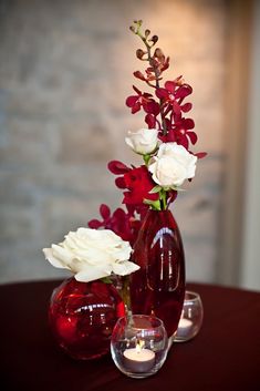 two vases with flowers and candles on a table