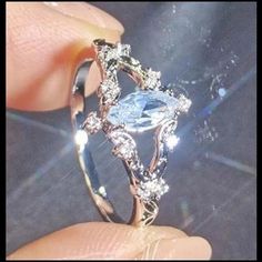 a person is holding a ring with an aqua and white diamond in it's center