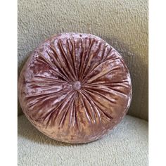 a round pillow sitting on top of a beige couch next to a white carpeted wall