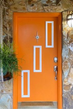 an orange front door with white trim and two planters