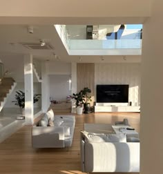 a living room filled with white furniture and a flat screen tv mounted on the wall