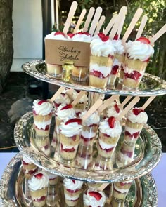 desserts are arranged on three tiered trays with strawberries and whipped cream