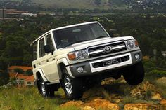 a white four door toyota truck driving down a hill