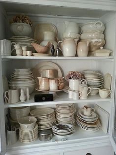 a white china cabinet filled with lots of dishes