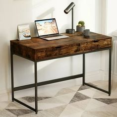 a desk with a laptop on it and a potted plant next to the table