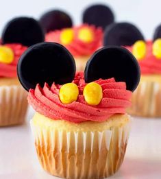 mickey mouse cupcakes with red frosting and yellow candies in the shape of ears