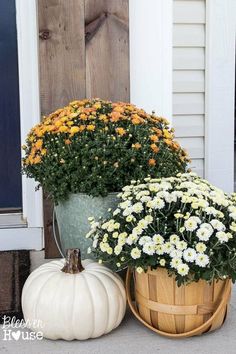 two buckets filled with white and yellow flowers sitting on the front step of a house