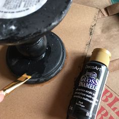 a close up of a person holding a paintbrush near a container with some glue on it