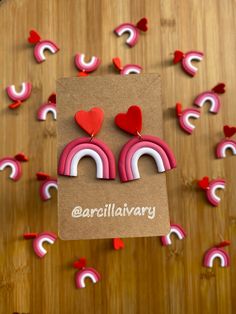 a pair of pink and white earrings with hearts on them sitting in front of a wooden table