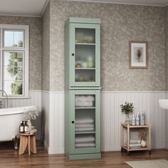 a bathroom with a green cabinet next to a white bath tub and wooden flooring