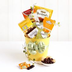 a yellow bucket filled with lots of different types of snacks and candies on top of a white table