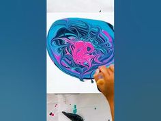 a person is drawing on a piece of paper with colored ink and watercolor pencils